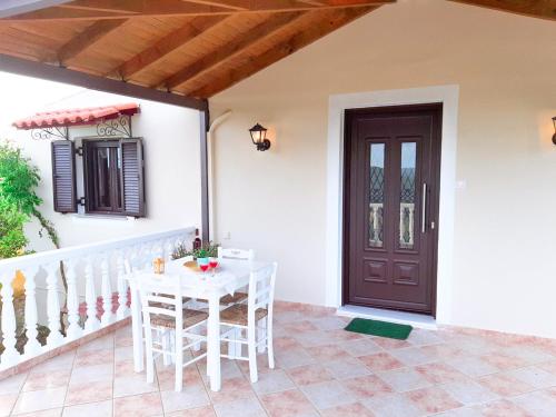 a porch with a white table and chairs and a door at Nature Villa in Volimes