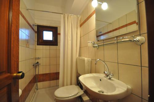 a bathroom with a sink and a toilet and a mirror at Guesthouse Papagiannopoulou in Zagora