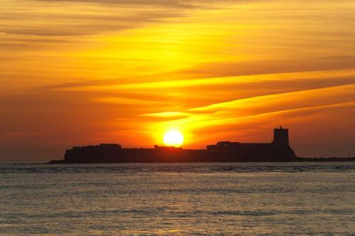 a sunset over the ocean with the sun in the sky at Hotel Azalea Playa in Chiclana de la Frontera