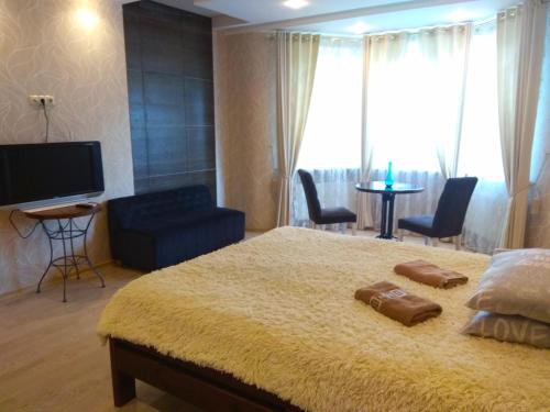 a bedroom with a bed and a tv and chairs at Apartment on Dubenskaya street in Rivne