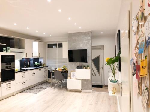 a kitchen with white cabinets and a dining room at Ferienwohnung Domizil am Delft Emden in Emden