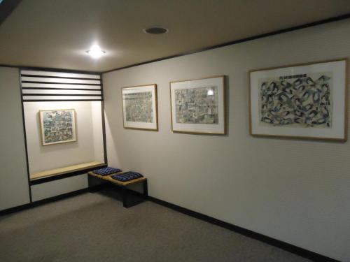 a room with three pictures on the wall and a bench at Yamagisi Ryokan in Fujikawaguchiko