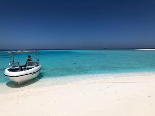 un hombre en un barco en el agua en una playa en Villa Kudì Maldives Guest House Thulusdhoo en Thulusdhoo