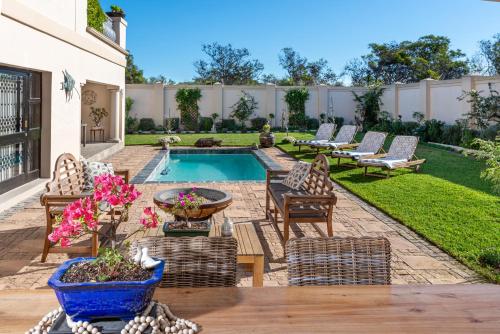 a backyard with a swimming pool with chairs and a table at Amery House in Port Elizabeth