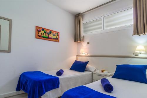 twee bedden in een kamer met blauwe kussens bij Alsol Patricio in Playa del Inglés