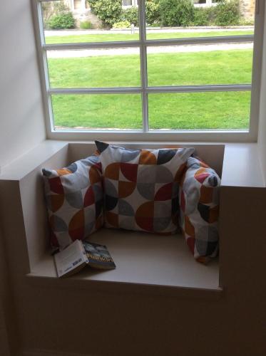 um assento na janela com duas almofadas e um controlo remoto em Brandoch Lodge em Logierait