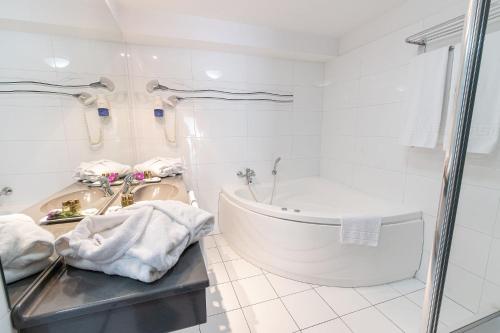 a white bathroom with a tub and a sink at Hotel Parliament in Bucharest
