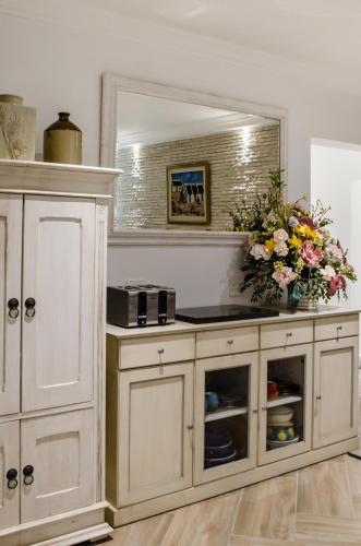 a white cabinet with a mirror and a vase of flowers at Somerset View Guest House in Somerset West