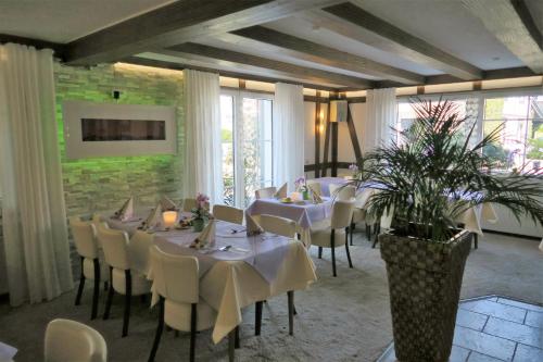 a dining room with white tables and chairs at Landhotel Bergischer Hof GmbH Marialinden in Overath