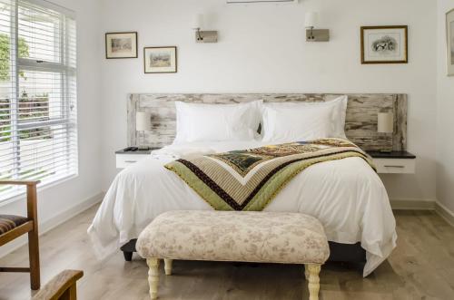 a bedroom with a large bed with a bench next to it at Somerset View Guest House in Somerset West