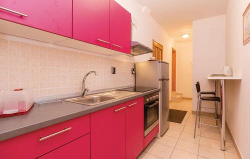 een keuken met rode kasten en een roestvrijstalen koelkast bij amz AP2 in Jadranovo