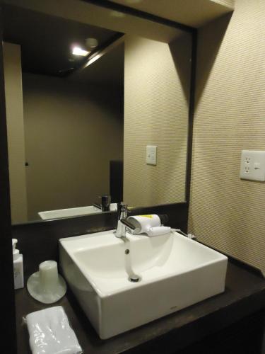 a bathroom with a white sink and a mirror at Yamagisi Ryokan in Fujikawaguchiko