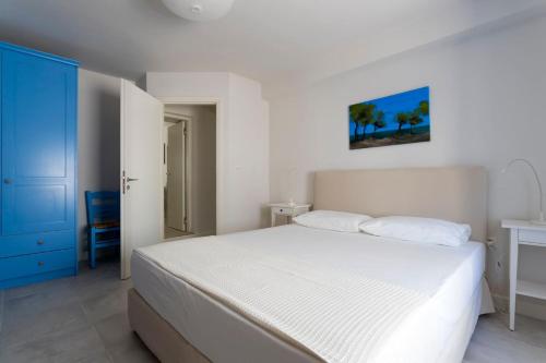a bedroom with a white bed and a blue door at The Palm Tree House!! in Spetses
