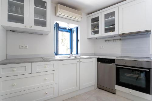 a kitchen with white cabinets and a sink and a window at The Palm Tree House!! in Spetses