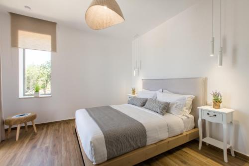 a white bedroom with a large bed and a window at Kallixeni Villas in Rethymno Town