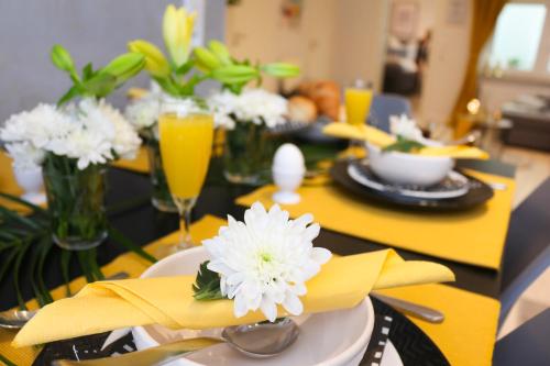 a dining table with yellow napkins and white flowers on it at Ferienwohnung Domizil am Delft Emden in Emden