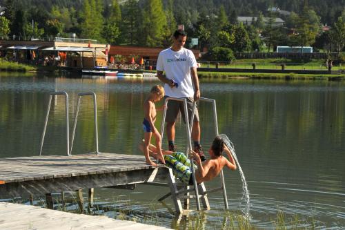 a man and two children standing on a dock in the water at A-VITA Viktoria & A-VITA living luxury apartments in Seefeld in Tirol