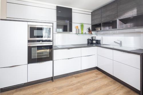 a white kitchen with stainless steel appliances and wood floors at Winkelschiffchen II mit Sauna in Juist