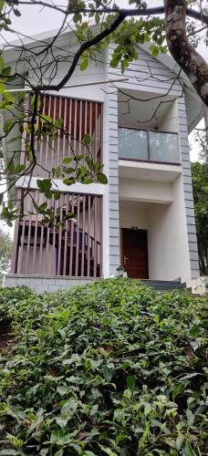 a white house with a gate and a lot of leaves at Holiday Vagamon in Vagamon
