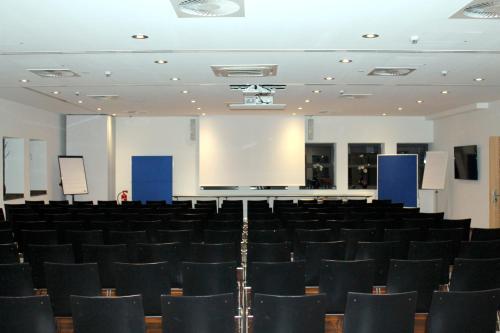 a lecture hall with black chairs and a screen at Heiner's Parkhotel in Gelsenkirchen