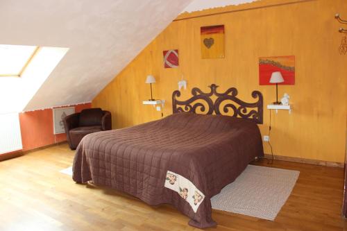 ein Schlafzimmer mit einem Bett und einem Stuhl im Dachgeschoss in der Unterkunft La part des anges in Pupillin