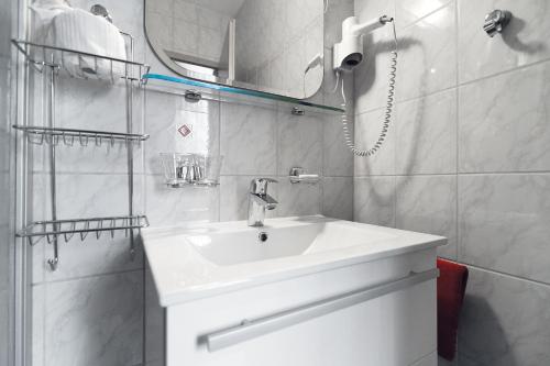 a white bathroom with a sink and a mirror at Hotel und Restaurant Bühlhaus in Eibenstock