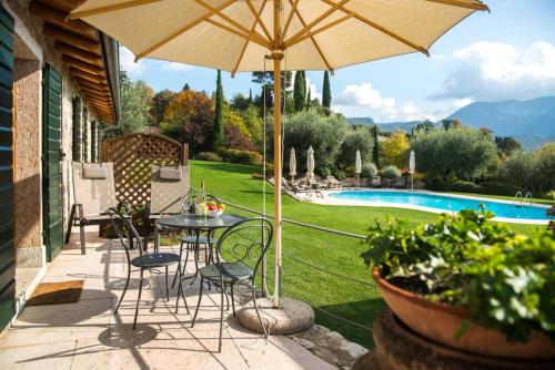 un patio con mesa, sillas y sombrilla en Agriturismo Ca del Baldo, en Caprino Veronese