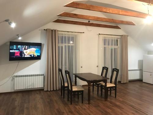 a dining room with a table and chairs and a tv at cozy apartments in Truskavets