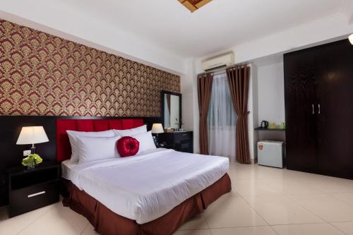 Hanoi Amore Hotel & Travel في هانوي: غرفة نوم عليها سرير ومخدة حمراء