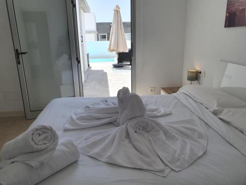 Una cama blanca con toallas encima. en Villa New York, en Playa Blanca