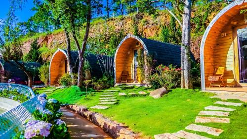 a garden with a wooden house with a lawn at Berry Valley Homestay in Da Lat