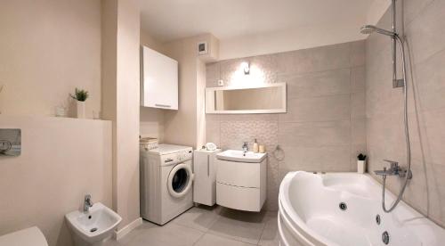 baño blanco con lavadora y lavamanos en CosmopolitApart, en Sibiu