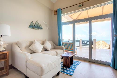 a living room with a couch and a sliding glass door at Ocean Breeze in Placencia Village