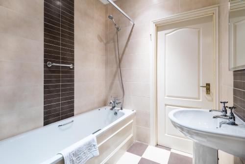 a bathroom with a bath tub and a sink at The Atholl Palace in Pitlochry