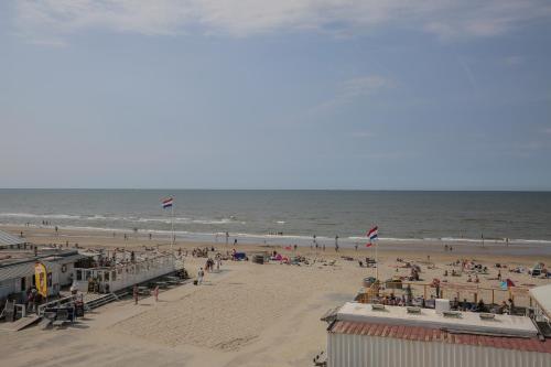 a beach filled with lots of beach chairs and umbrellas at Fletcher Hotel Restaurant Zeeduin in Wijk aan Zee