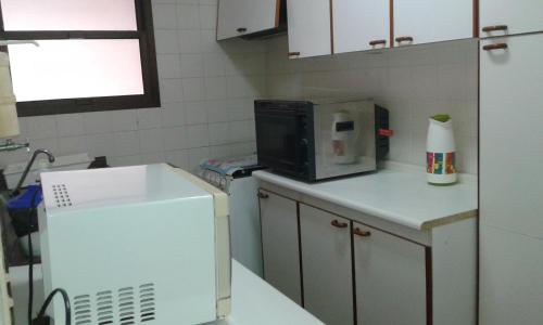 a kitchen with a microwave and a refrigerator at Residencial flat Golden beach.. in Guarujá