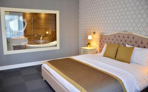 Hotel Konak في مومتشيلغراد: غرفة نوم مع سرير كبير ونافذة مع حوض استحمام