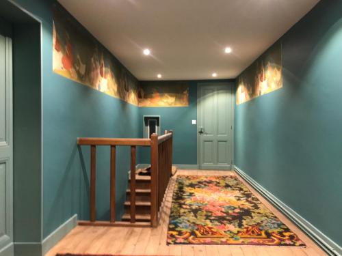 a hallway with blue walls and a staircase with a rug at La Rebière d'Or, B&B et Gîte in Mouleydier