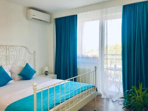 1 dormitorio con 1 cama con cortinas azules y ventana en Pipera Lake View Bright Apartament, en Bucarest