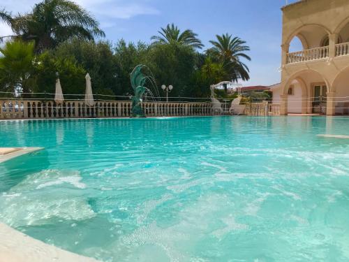 a swimming pool in a resort with blue water at Villaggio San Giovanni in San Giorgio Ionico