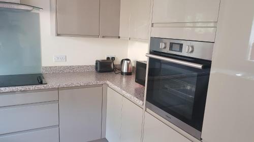 a kitchen with white cabinets and a black oven at Luxurious Dingle Corner in Bristol