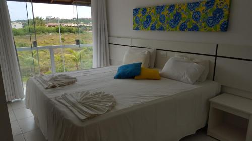 a white bed with two pillows and a window at Condomínio Mar da Galiléia - Apto 27 in Porto Seguro