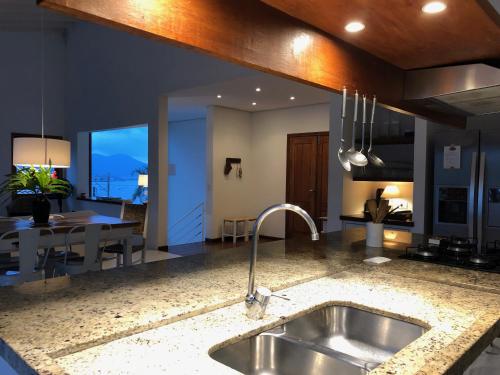 uma cozinha com um lavatório de aço inoxidável e uma mesa em CASA PIÚVA em Ilhabela