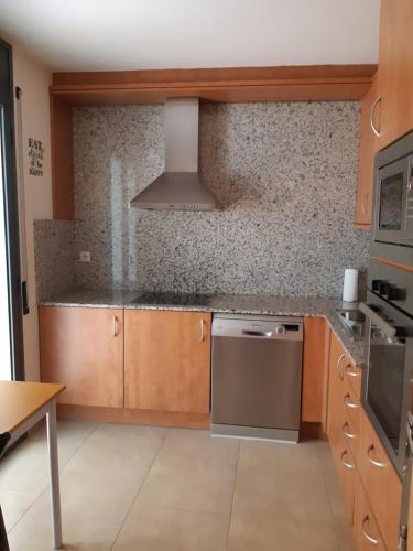 a kitchen with wooden cabinets and a stove at Cal Ribero in Villanova de la Sal