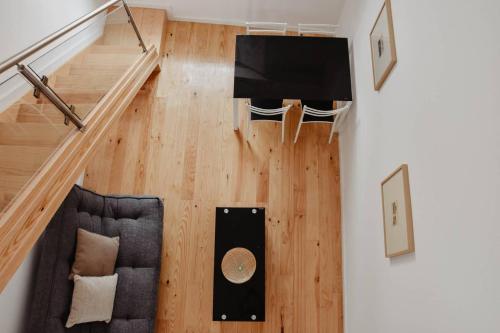 a living room with a couch and a television on a wooden floor at T1 central e calmo, moderno e acolhedor em Coimbra - Self check in in Coimbra