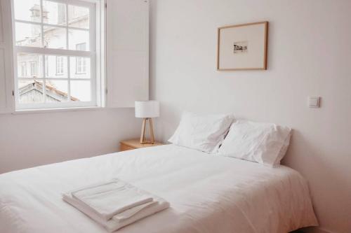 a white bed in a room with a window at T1 central e calmo, moderno e acolhedor em Coimbra - Self check in in Coimbra