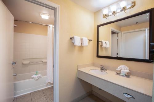 a bathroom with a sink and a mirror and a tub at staySky Suites I-Drive Orlando Near Universal in Orlando