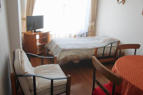 1 dormitorio con 2 camas, 2 sillas y TV en Apart Hotel Carampangue en Valdivia