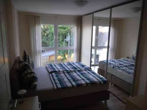Schlafzimmer mit einem Bett, einem Spiegel und einem Fenster in der Unterkunft Ferienwohnung Bernkastel-Kues - Alte Rebschule in Bernkastel-Kues
