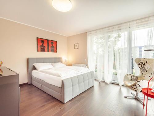 a bedroom with a white bed and a large window at VacationClub - Pionierów 6, Apratament 31 in Mielno